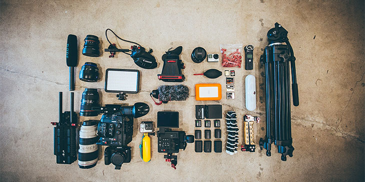 filmmaking equipment arranged on a concrete floor including cameras, microphones, and a tripod